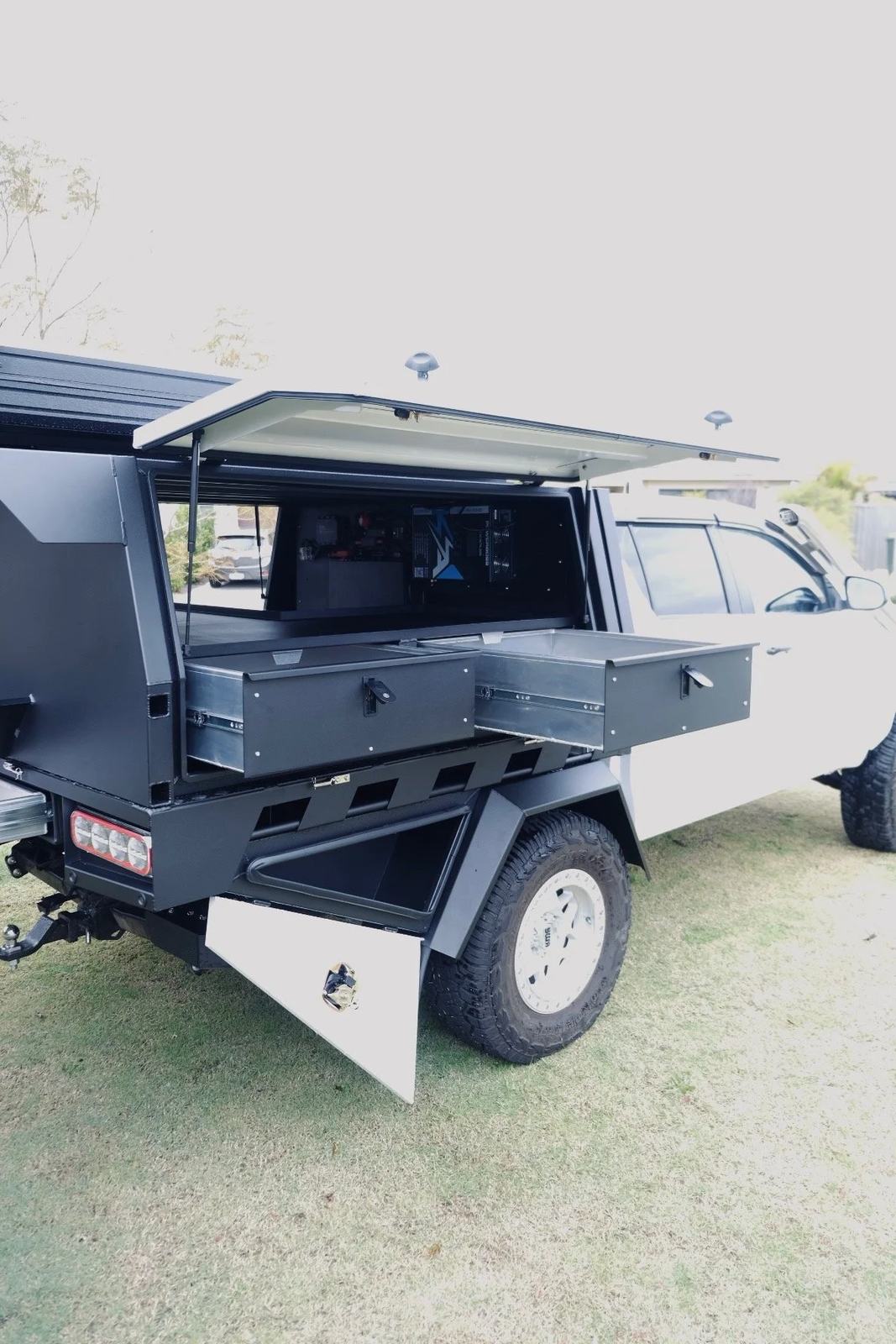 Canopy with gull-wing door open revealing drawers and a fold-down side table